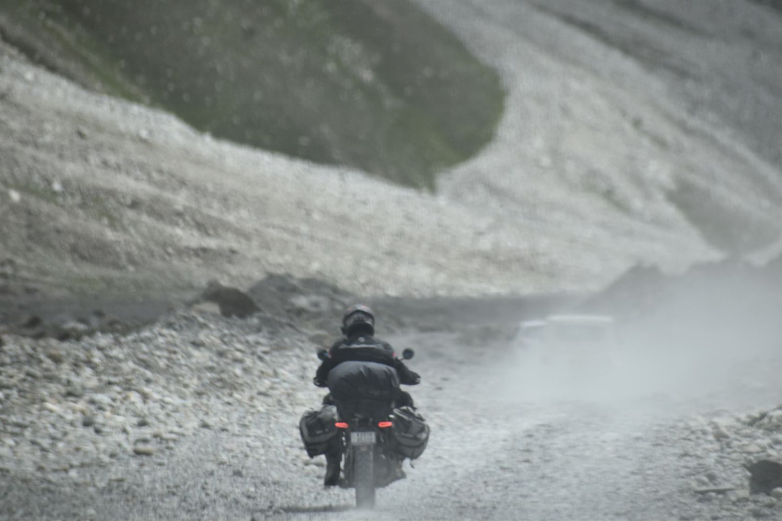 A rider heading away down a dusty high-altitude trail